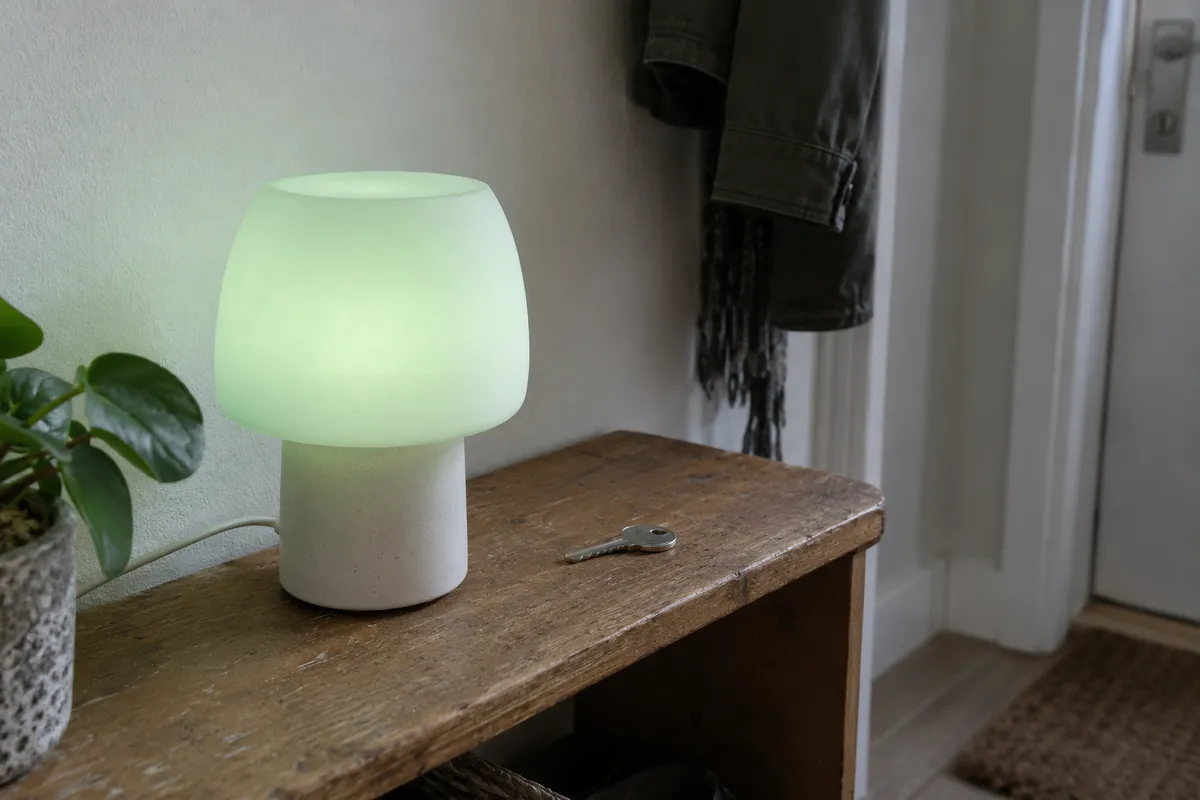 A small lamp glowing pale green on a hallway shelf beside a key